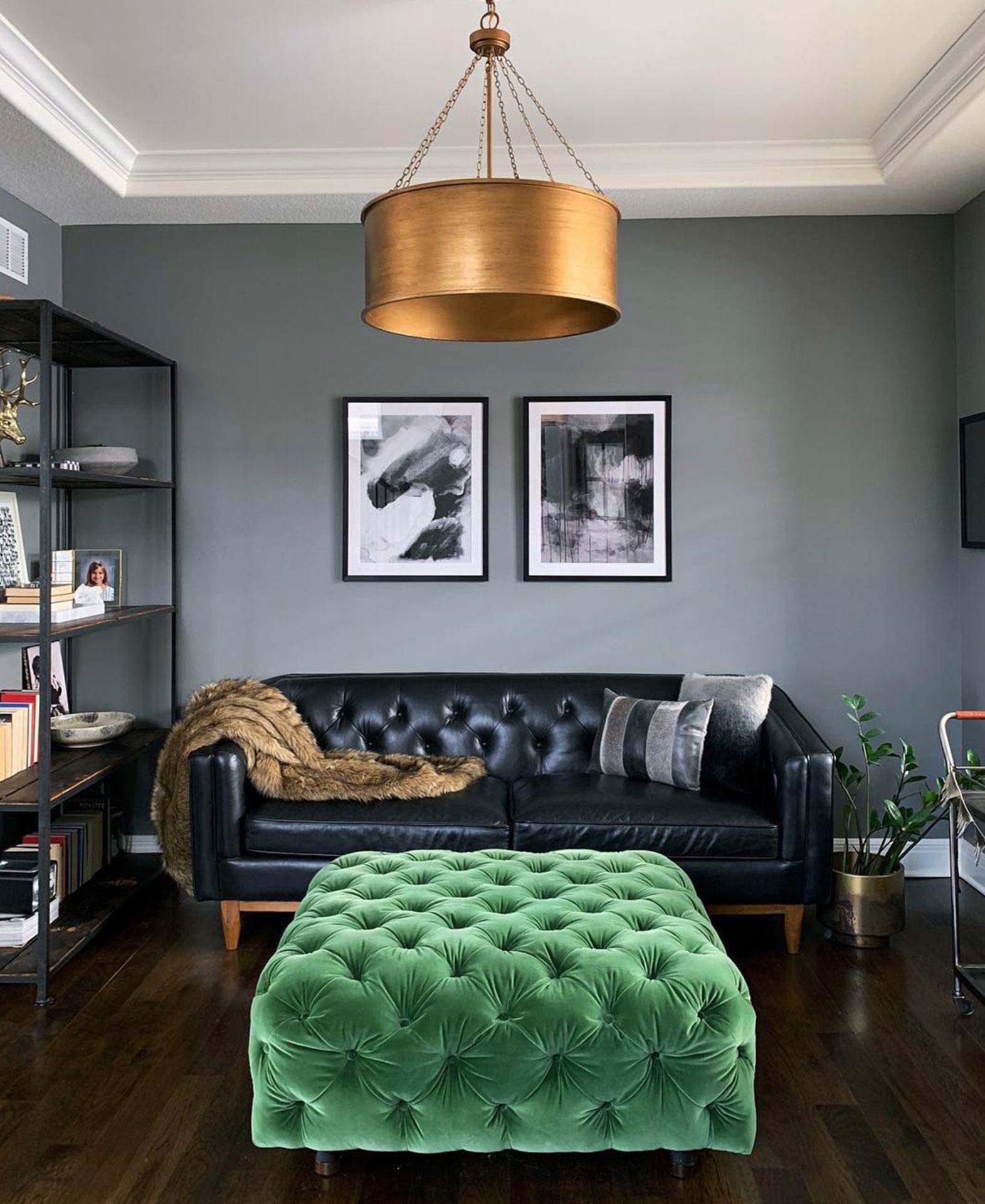 Sofá preto de couro Alcott numa sala de estar com um pouf de veludo verde esmeralda's black Alcott Leather sofa in a living room with a green emerald velvet pouf