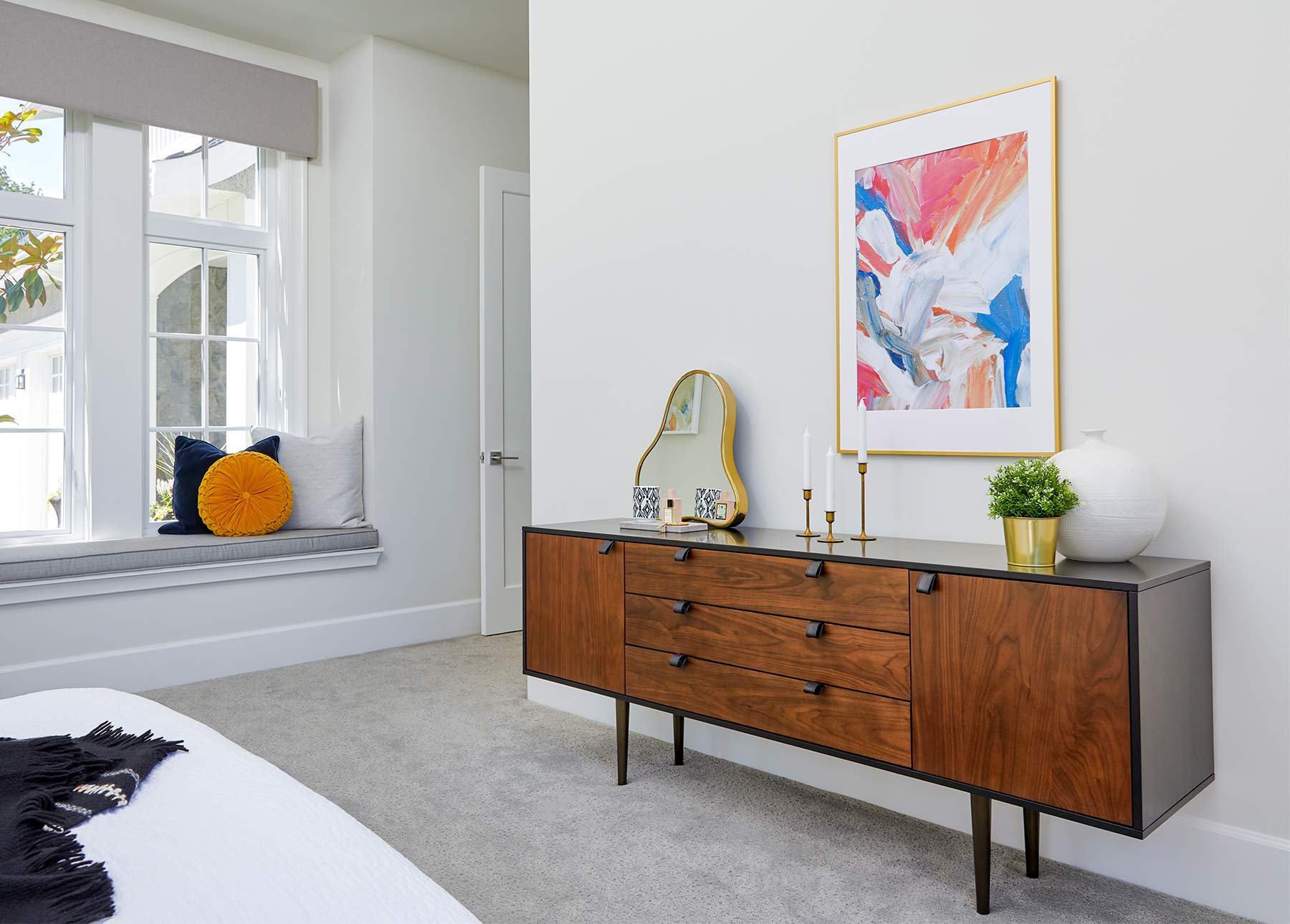 Envelo Sideboard ditampilkan di kamar tidur modern dengan karya seni berwarna-warni dan cermin lonjong.